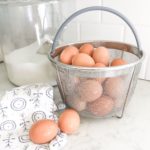 brown eggs in Instant Pot Steamer basket with tea towel on white counter