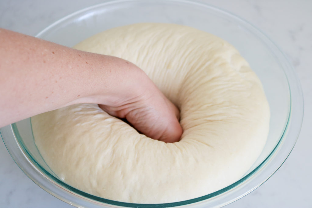 fist punching down homemade bread dough