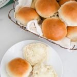homemade rolls in a wire basket with some butter on top