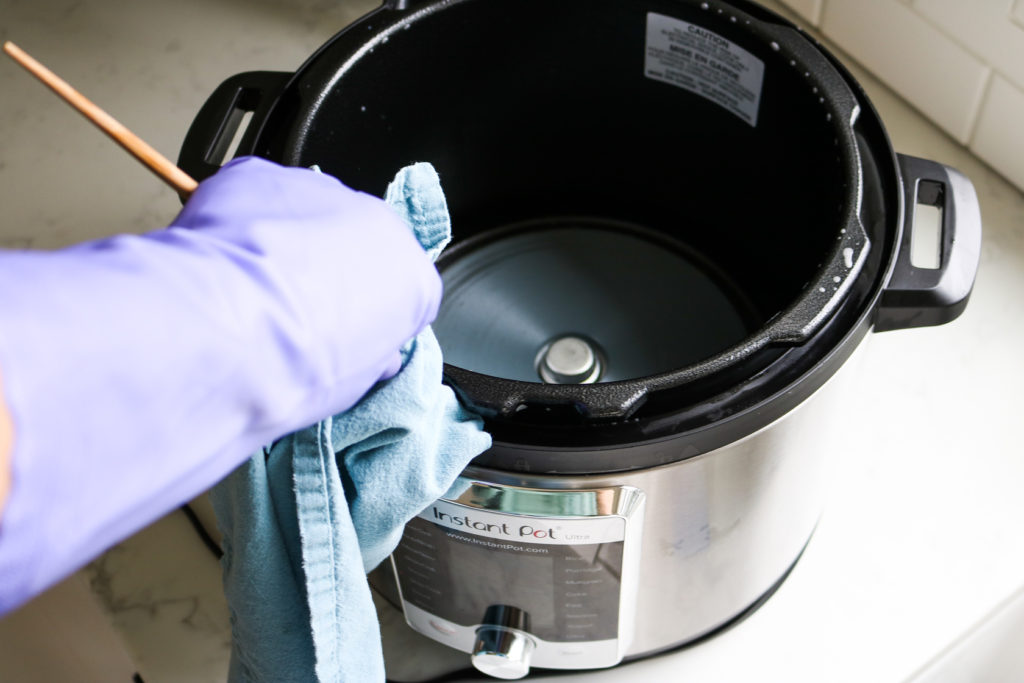 gloved hand cleaning the instant pot rim