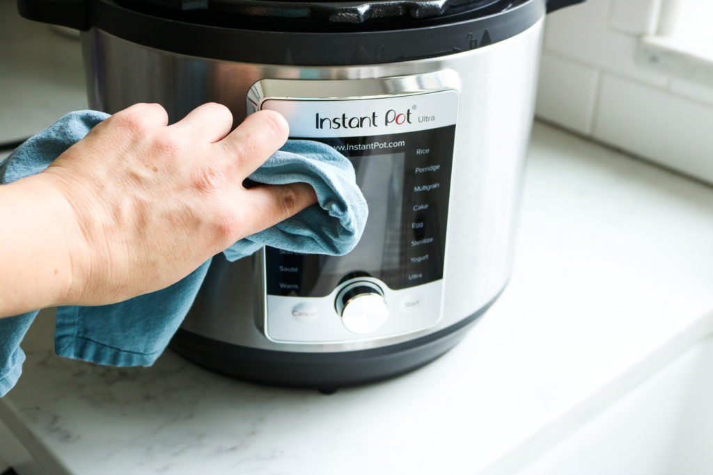 hand wiping down and cleaning outside of instant pot