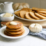 Stack of gluten free pumpkin pancakes with white mini pumpkin