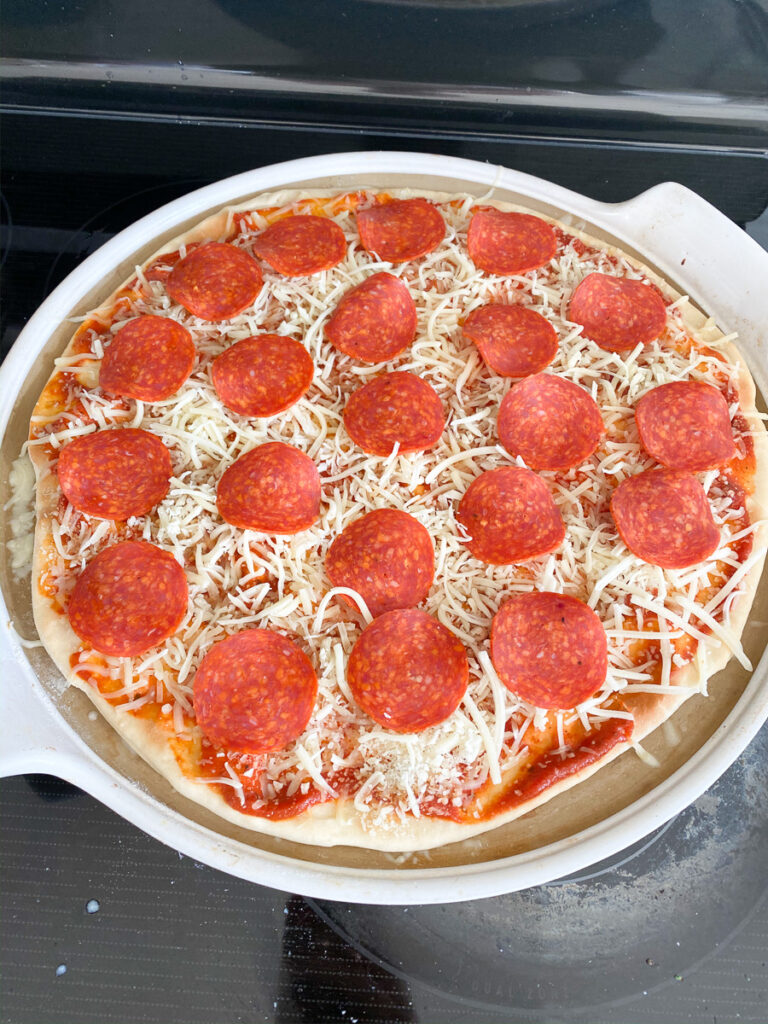 raw pepperoni pizza on pan